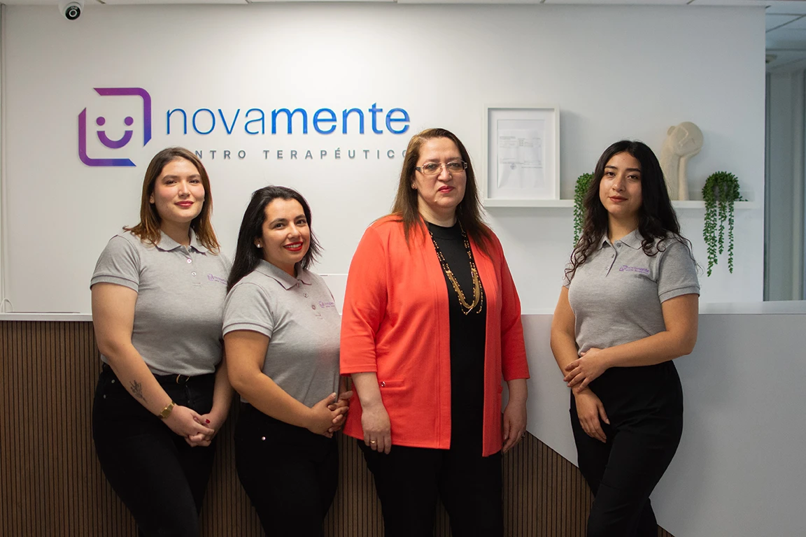 Cuatro profesionales de Novamente en formación institucional frente a la marca del centro en Santiago.